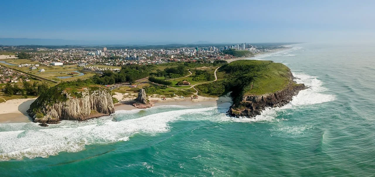 Vista aérea da Praia da Guarita, com falésias, mar e a cidade de Torres ao fundo